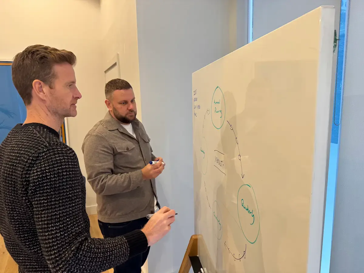 Mark and Rikki at a whiteboard, Rikki writing out a sitemap