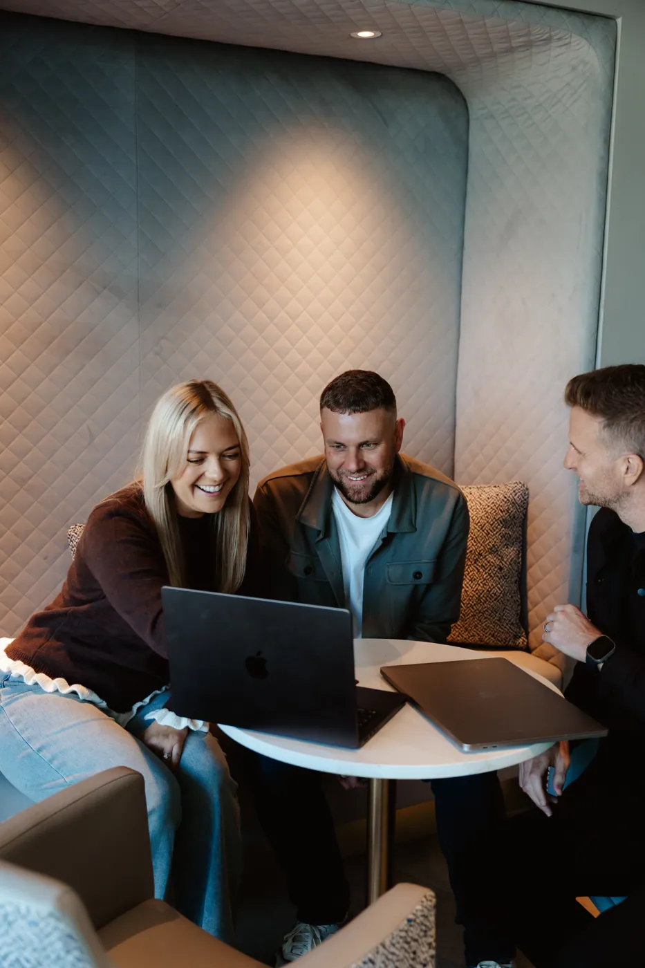 Emma, Rikki and Mark around a laptop in a booth