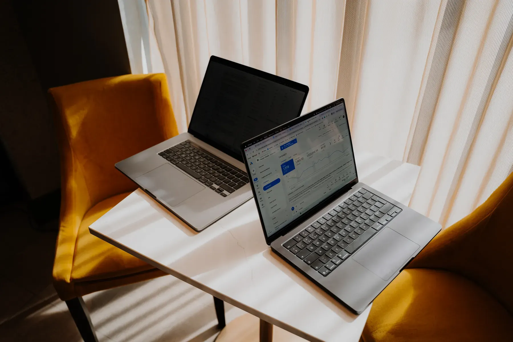 Two laptops between armchairs